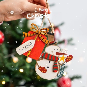 Wooden Christmas ornaments set featuring Joy gift box and Snowman held against blurry lights