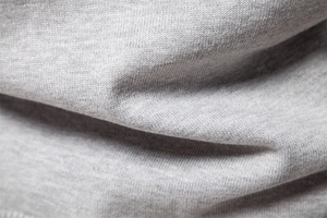 Macro shot of light gray knit fabric texture showing soft cotton blend fibers and weave