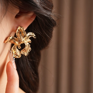 Close-up of elegant gold irregular flower earring worn by a model to show size and style