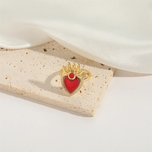 Detailed macro view of gold heart ring with red stone on beige stone and white silk background