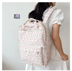 Girl wearing a white floral backpack with pink flowers in a minimalist studio setting