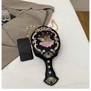 Detail of baroque embroidery on black mirror-shaped crossbody bag with pearl chain strap