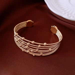 Detail view of gold multi-layer beaded open cuff bracelet on elegant satin fabric