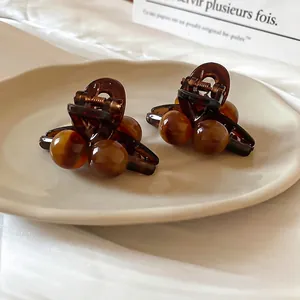 Elegant tortoiseshell acrylic hair clips set with gold metal spring on a ceramic tray