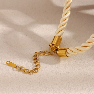 Close-up of gold lobster clasp and extension chain on beige braided rope necklace