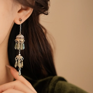 Close-up of vintage gold flower earrings with zircon tassels and green teardrop beads