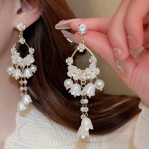 Elegant gold flower earrings with pearls and crystals shown on a model for a resort style look