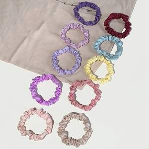Set of ten colorful satin silk scrunchies arranged on a clean minimalist background