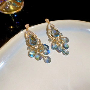Close-up of vintage gold earrings with blue crystal teardrops and tassel beads