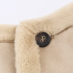 Close-up of light brown jacket featuring soft beige faux fur collar and wood texture button