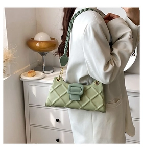 Quilted light green baguette bag with woven strap shown on shoulder for size perspective
