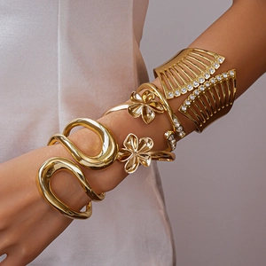 Detailansicht goldener Armreif und Armbänder mit Blumenmuster und weißen Strasssteinen