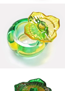 Close-up of a gradient green and yellow glass nail art jar with a flower-shaped lid