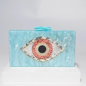 Close-up of marble acrylic clutch with evil eye glitter detail on white geometric stand