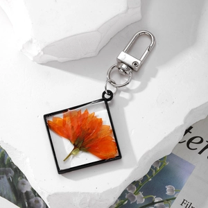 Square pendant with orange dried flower and silver lobster clasp on stone background