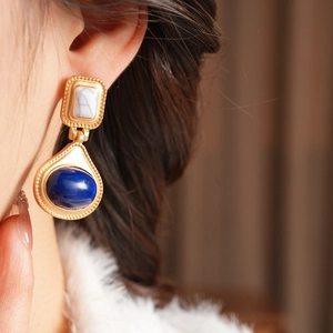 Close-up of vintage resin earrings with white marble and blue drop stones on model