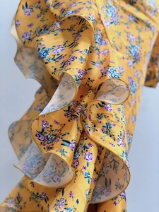 Detail of yellow floral dress showing layered ruffle textures and chiffon fabric