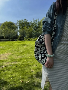 Detail of green floral canvas tote bag with matching scrunchie on outdoor park background