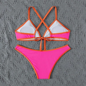 Flat lay of pink and orange contrast bikini set with adjustable straps and cross back