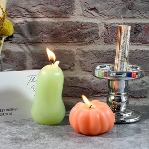 Macro di candele realistiche a forma di pera e zucca accese su uno sfondo in pietra rustica