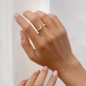 Detail of adjustable gold leaf ring with white marquise zircons worn on finger