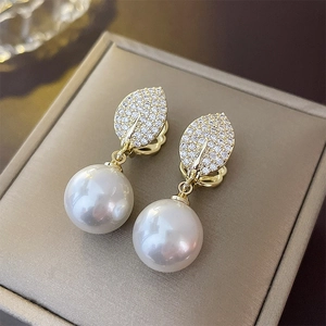Macro view of gold plated leaf earring with zircon pave and large white pearl detail