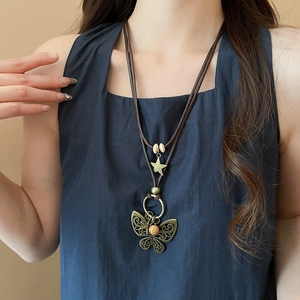 Close-up of vintage butterfly pendant with wooden beads on a brown wax cord necklace