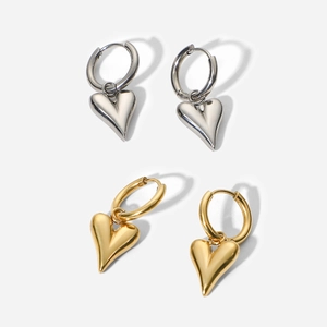 Detailed close-up of heart pendant earrings in polished silver and gold finishes