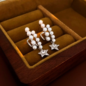 Macro shot of pearl earrings with zircon star charms in a black velvet jewelry box