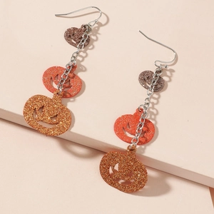 Macro detail of three-tier sparkling glitter pumpkin earrings for Halloween fashion