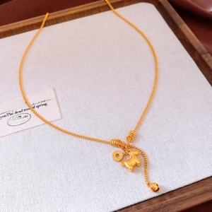 Detailed shot of gold plated horse and coin pendants on a minimalist necklace