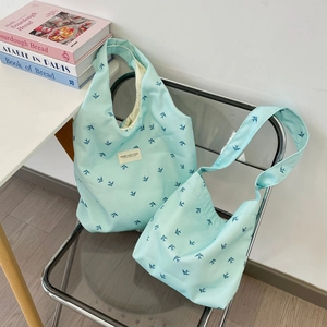 Gros plan de sacs cabas en toile vert menthe à motifs d'oiseaux sur une chaise en acrylique