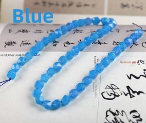 Macro detail of faceted blue chalcedony beads arranged on a calligraphy background