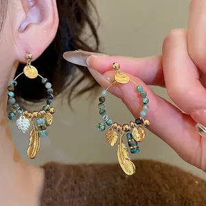 Bohemian gold plated feather pendant earrings with turquoise beads on model