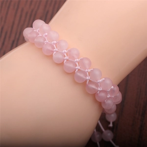 Detail of pink crystal double-row woven bracelet on wrist over a dark wooden background