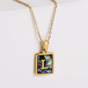 Macro view of 18k gold square pendant with colorful shell texture and letter L engraving