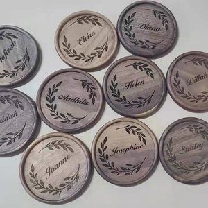 Close-up of circular wooden coasters featuring custom engraved names and laurel wreaths