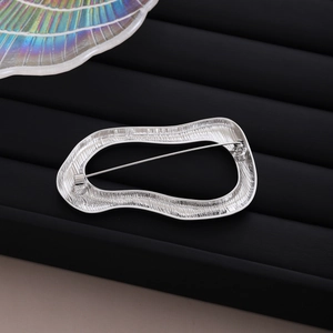 Minimalist irregular oval silver brooch with vertical texture on black striped base