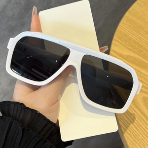 Close-up of stylish white oversized sunglasses with dark grey lenses in hand