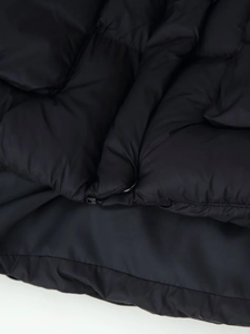 Detailed macro view of black puffer jacket showing quilted fabric texture and stitching