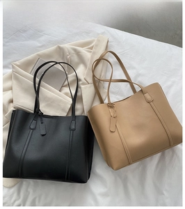 Minimalist soft leather tote bags in black and camel shown in a lifestyle still life setting