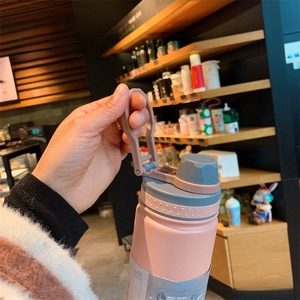 Close-up of pink stainless steel sports bottle featuring a foldable handle and silicone grip
