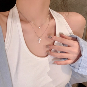 Detailed view of layered 925 silver necklace with moissanite cross pendant on model