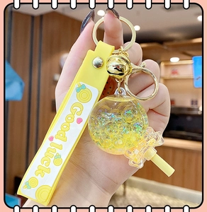 Close-up of yellow lollipop keychain with glitter sand and Good luck strap detail