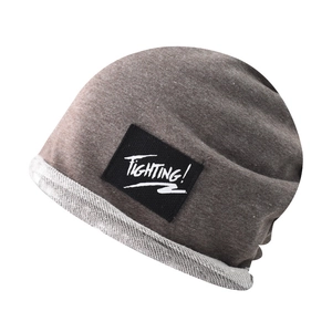 Close-up of coffee grey knit beanie featuring a black Fighting label and rolled edge