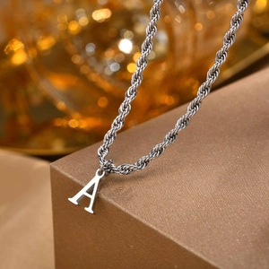 Macro shot of a silver letter A pendant featuring a detailed twisted rope chain texture