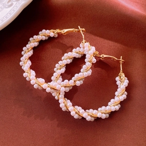 Detail of vintage gold-plated hoop earrings with woven small white pearls on red fabric