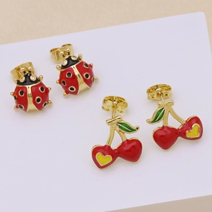 Cute red enamel ladybug and cherry earrings with gold metal base on display