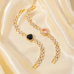 Detail of gold bracelets with heart-shaped pink and blue stones and triple-row zircons
