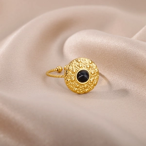 Detail of adjustable gold sun ring with black stone on champagne satin fabric background